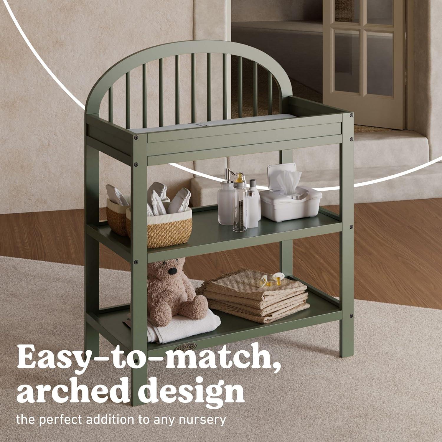 imageGraco Olivia Changing Table with WaterResistant Changing Pad Driftwood GREENGUARD Gold Certified Includes Bonus WaterResistant Changing Pad with Safety Strap 2 Open Shelves Stylish DesignOlive