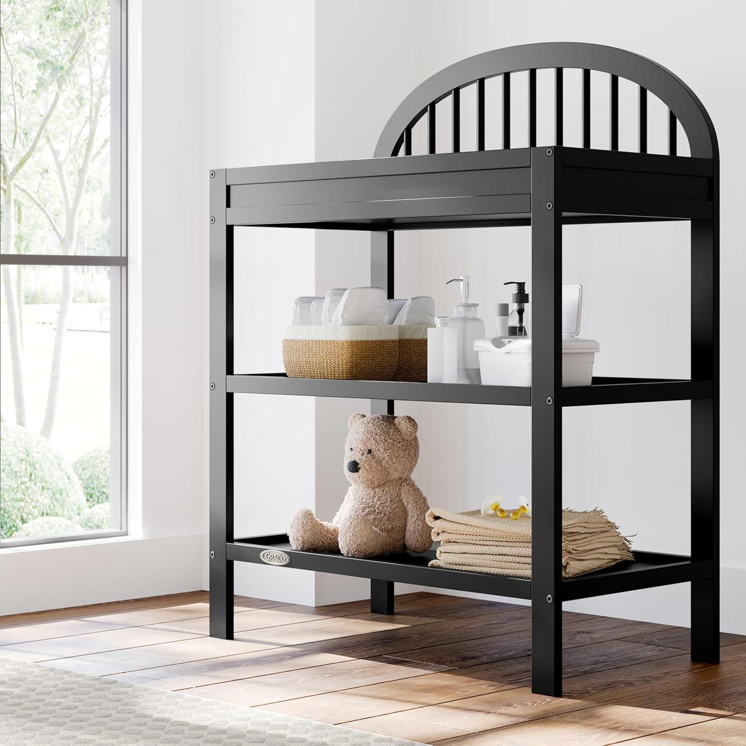 imageGraco Olivia Changing Table with WaterResistant Changing Pad Driftwood GREENGUARD Gold Certified Includes Bonus WaterResistant Changing Pad with Safety Strap 2 Open Shelves Stylish DesignBlack