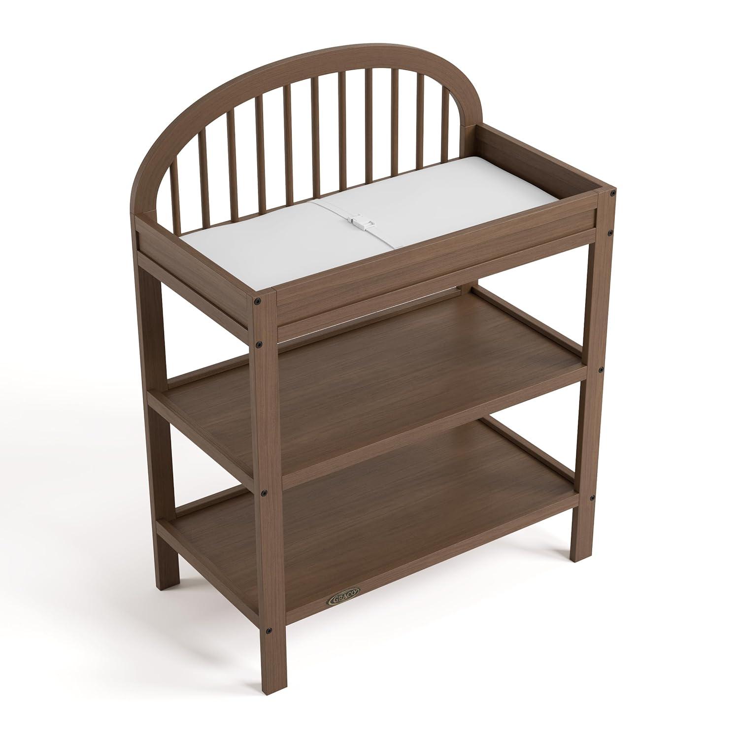 imageGraco Olivia Changing Table with WaterResistant Changing Pad Driftwood GREENGUARD Gold Certified Includes Bonus WaterResistant Changing Pad with Safety Strap 2 Open Shelves Stylish DesignHazelnut