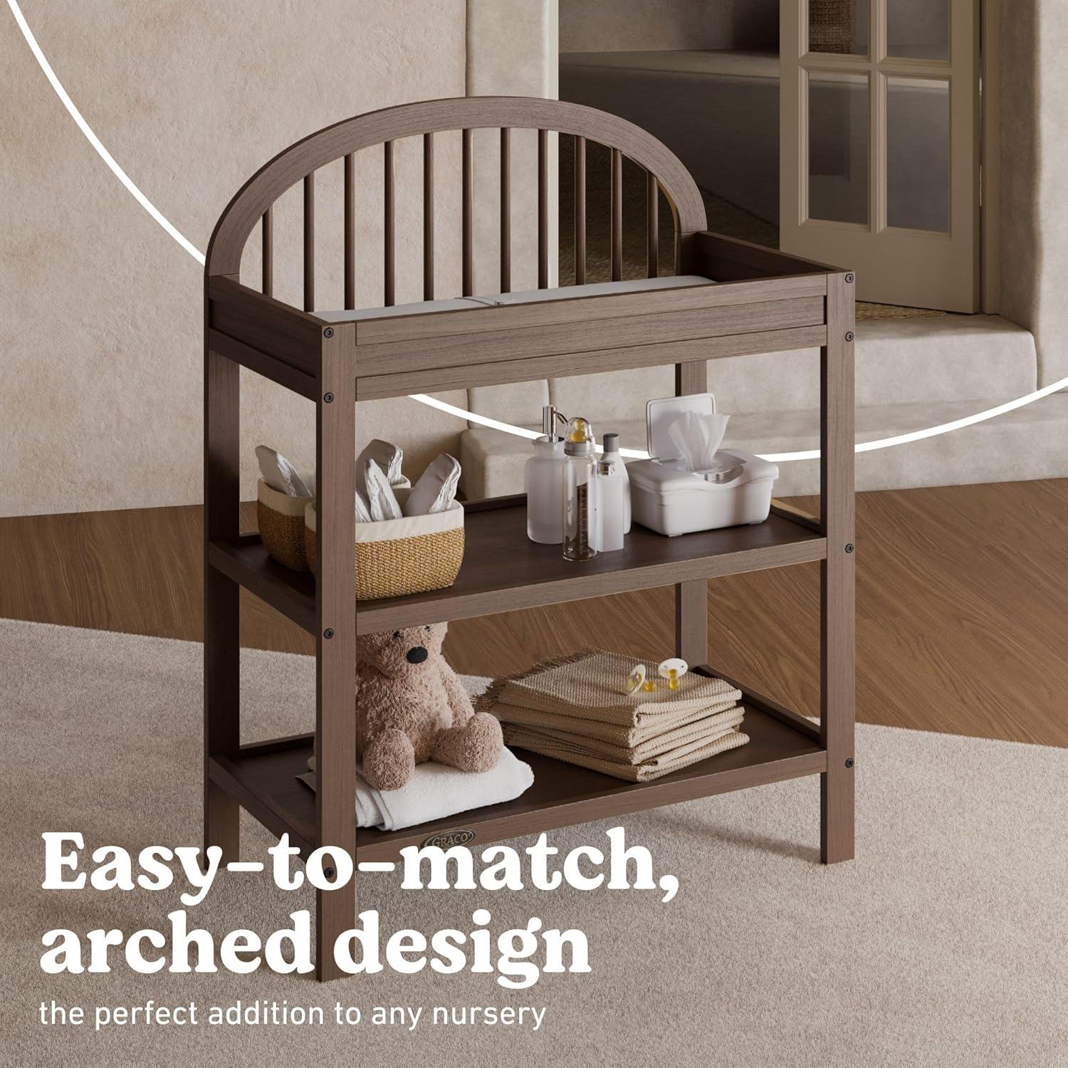 imageGraco Olivia Changing Table with WaterResistant Changing Pad Driftwood GREENGUARD Gold Certified Includes Bonus WaterResistant Changing Pad with Safety Strap 2 Open Shelves Stylish DesignHazelnut